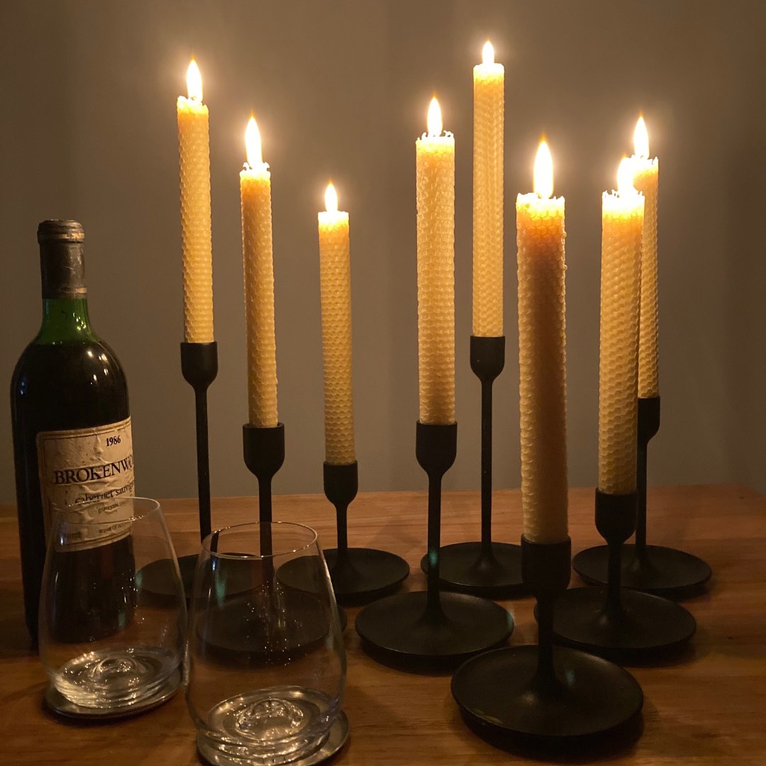 8 beeswax dinner candles in a dining table with a bottle of red wine and wine glasses